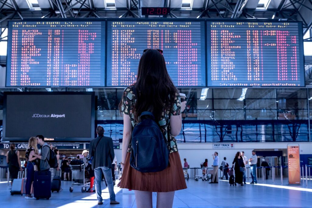 A girl standing in front of the screen in the airport.